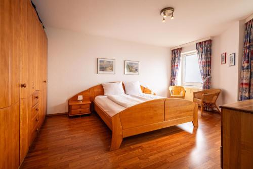 a bedroom with a wooden bed with a wooden floor at Gemütliche Ferienwohnung mit Wintergarten & Meerblick am Südstrand Wohnung 123 in Wilhelmshaven