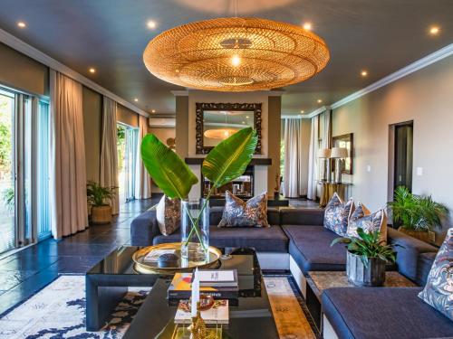 a living room with blue couches and a large chandelier at Luxury Villa Umdoni - Eden Rock Estate, Pennington in Pennington