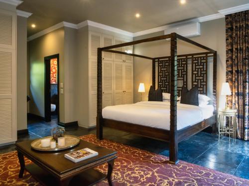 a bedroom with a canopy bed and a coffee table at Luxury Villa Umdoni - Eden Rock Estate, Pennington in Pennington