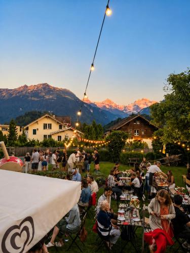 a crowd of people sitting around tables at an outdoor event at Adventure Hostel Interlaken in Interlaken