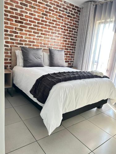 a bed in a room with a brick wall at 161 green valley in Boschrand