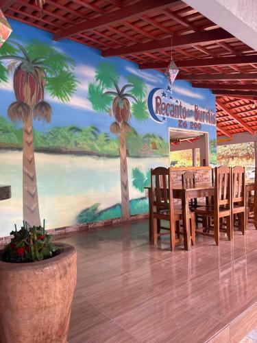 a dining room with a table and palm trees on the wall at Pousada Recanto dos Buritis in Manhã