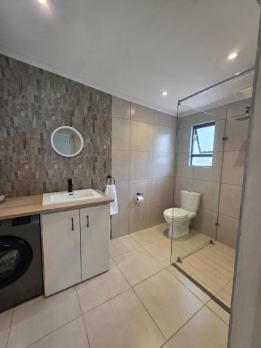 a bathroom with a toilet and a sink and a shower at Beach cottage in Gonubie Park