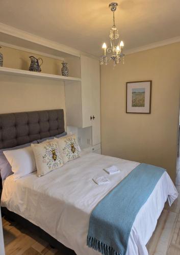 a bedroom with a large white bed with a chandelier at Beach cottage in Gonubie Park