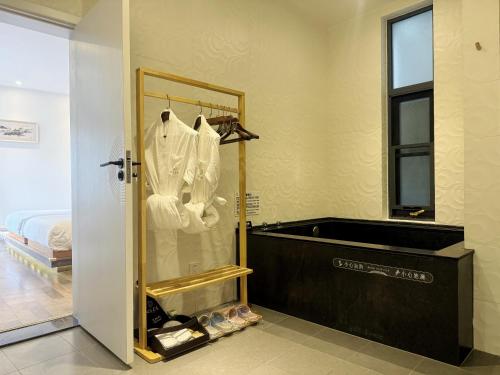 a bathroom with a bath tub and a robe at Xinyue Suying Hot Spring Holiday Hotel in Tengchong