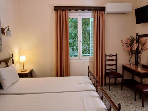 a bedroom with two beds and a desk and a window at Pension Alkistis in Tolo