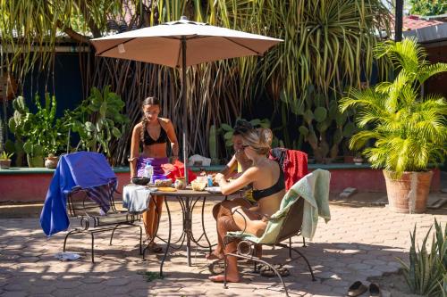 two women sitting at a table under an umbrella at Nopalero Hostel in Puerto Escondido