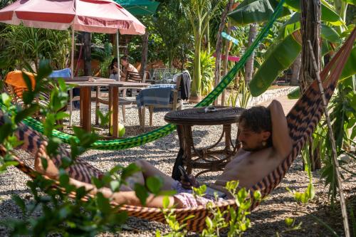 a man sitting in a hammock in a garden at Nopalero Hostel in Puerto Escondido