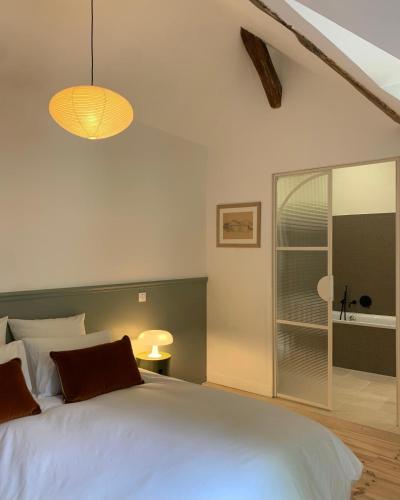 a bedroom with a large white bed with a glass door at La Papote in Bourron-Marlotte