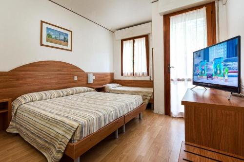 a bedroom with a bed and a flat screen tv at Hotel Eden in Lignano Sabbiadoro