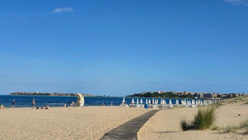 a beach with people and umbrellas and the ocean at Sunny Steps Hostel in Sunny Beach