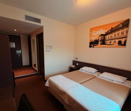 a bedroom with a bed and a painting on the wall at Hôtel de La Cloche in Dole