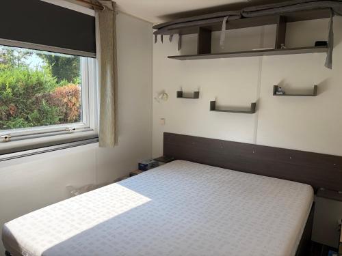 a small bedroom with a bed and a window at Mobil-home proche plage in Saint-Julien-en-Born