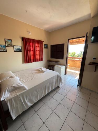 a bedroom with a white bed and a window at Bela Vista in Canoa Quebrada