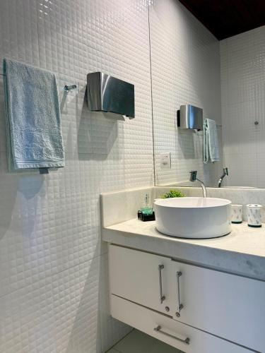 a white bathroom with a sink and a mirror at Mini Casa-Aconchego e Fitness in Pirenópolis