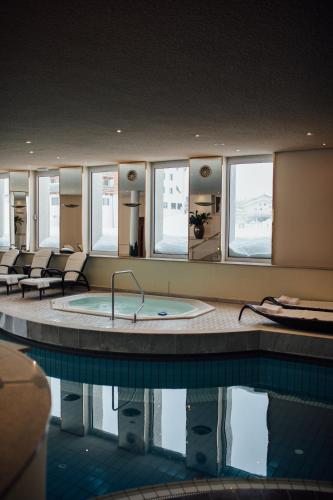 a large swimming pool with a tub in a building at Hotel Zürserhof in Zürs am Arlberg
