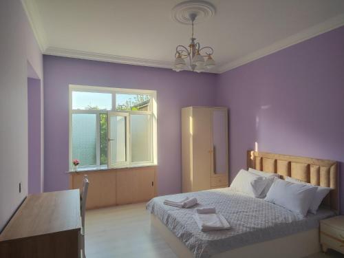 a bedroom with purple walls and a bed with two towels on it at Bright Modern Suite in Quba