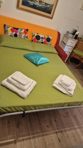 a bed with green sheets and white towels on it at La casetta di Nino in Termoli