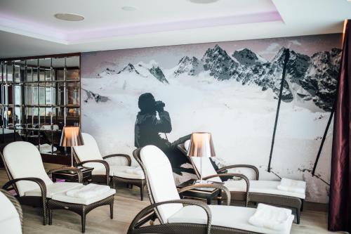 a room with chairs and a wall with a painting of a person at Hotel Zürserhof in Zürs am Arlberg