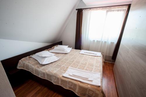 1 dormitorio con 1 cama con toallas y ventana en Pensiunea Morariu, en Bistriţa
