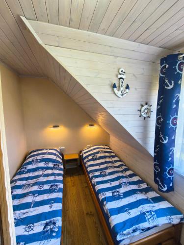 two beds in a small room with wooden walls at Domki Gama-Spa in Władysławowo
