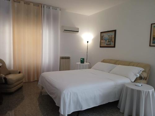 a bedroom with a large white bed and a chair at L'angolo di Rosa in Campofelice di Roccella
