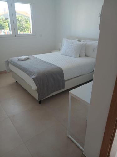 a white bedroom with a bed and a window at Casa Cabeça in Macedo de Cavaleiros