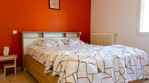 a bedroom with a bed with an orange wall at La Maison Du Vigneron in Gaillac