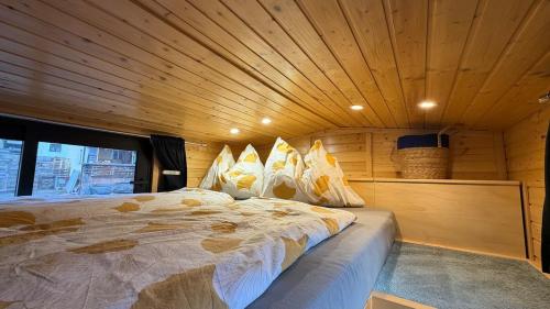 a bed in a room with a wooden ceiling at Tiny House nähe Millstättersee mit Hot Tub in Oberkolbnitz