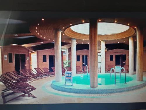 a swimming pool in a building with chairs at KASTELY ViLLA MISKOLCTAPOLCA in Miskolc