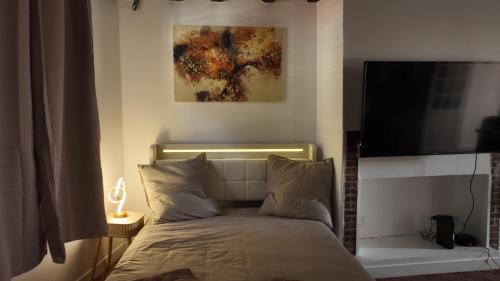 a bedroom with a bed with a flat screen tv at Appart proche gare centre ville bureau parking in La Loupe