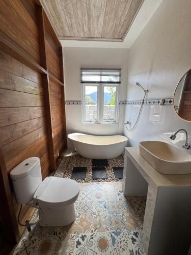 a bathroom with a tub and a toilet and a sink at Kanda Homestay in Sidemen