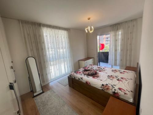 a bedroom with a bed and a large window at Leni Apartment in Patza-Kuqani