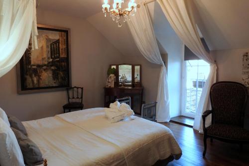 a bedroom with a white bed and a chandelier at Le Piano in Biesles