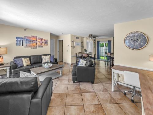 a living room with couches and a clock on the wall at Put-in-Bay Poolview Condo #2 in Put-in-Bay