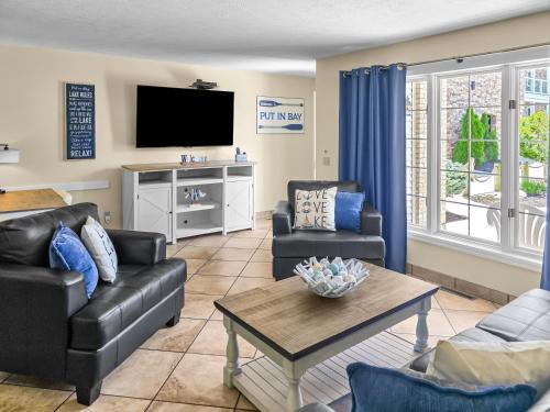 a living room with couches and a tv and a table at Put-in-Bay Poolview Condo #2 in Put-in-Bay