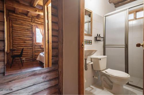 a bathroom with a toilet and a wooden wall at Olimpo Interior in Santa Elena