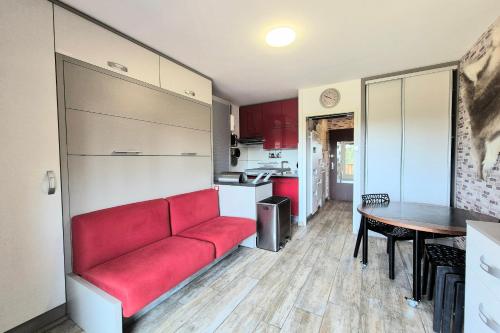 a living room with a red couch and a table at Cozy apartment "WAPITI" at the foot of the slopes in Les Déserts