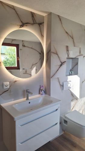 a bathroom with a sink and a mirror and a toilet at Hidden Haven Cottage Sarajevo in Lokve