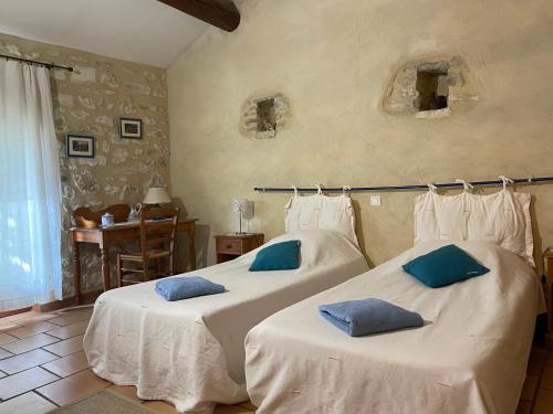 a bedroom with two beds with blue pillows on them at La Ferme Terre Bio Provence in Lapalud