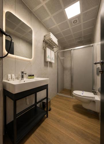 a bathroom with a sink and a toilet and a mirror at Nora Airport Hotel in Arnavutköy