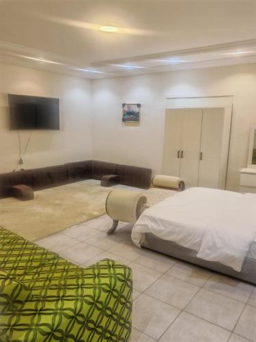 a bedroom with a bed and a couch and a tv at hostel in Obhur in Jeddah