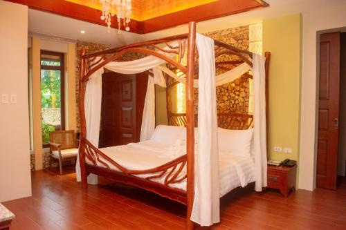 a bedroom with a four poster bed with white sheets at Katunggan Cove Resort in Nueva Valencia