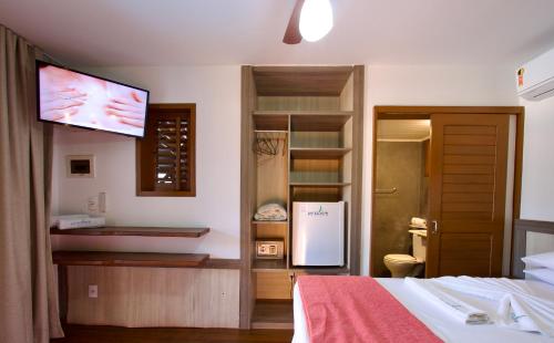 a bedroom with a bed and a tv on the wall at Pousada Windjeri in Jericoacoara