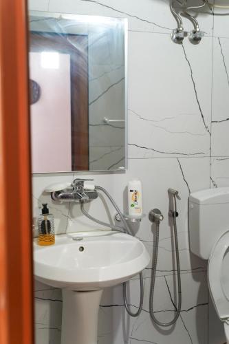 a bathroom with a sink and a mirror and a toilet at ARBERs aparthotel in Durrës
