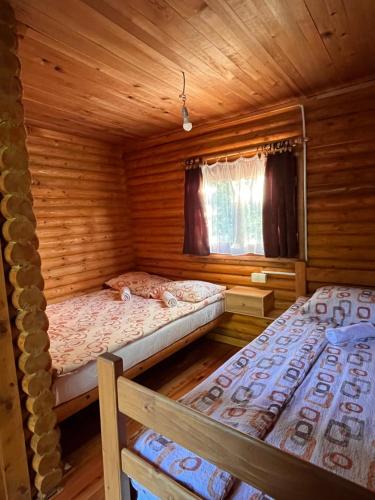two beds in a log cabin with a window at Rafting Centar Bato in Plužine