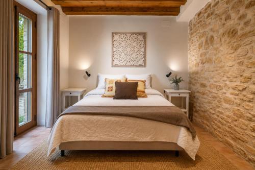 a bedroom with a large bed and a brick wall at El Gresol - Naturaleza y Relax in Senant