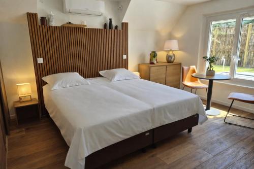 a bedroom with a large white bed and a table at Lodge avec piscine chauffée privative et ou Studio avec son SPA, SAUNA HAMAMM privatifs in Cepoy