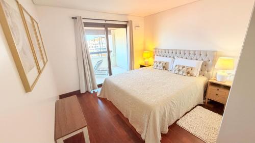 a bedroom with a bed and a door to a balcony at Seaside one bedroom apartment with terraces, garage & swimming pool in Cascais