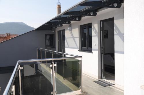 a balcony with glass railings on a white house at Rooms Villa Downtown in Mostar